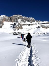 Rear view of people on snow covered mountain against sky