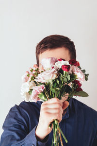 Young woman holding bouquet against white background