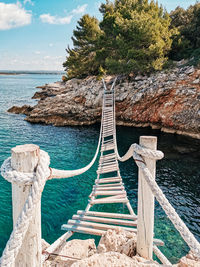 Old wooden rope bridge. foot bridge over water, sea, summer.