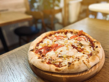 Pizza with chicken, tomatoes, corn and mozzarella is on the table in a plate. restaurant food. 