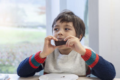 Cute boy eating food while sitting at home