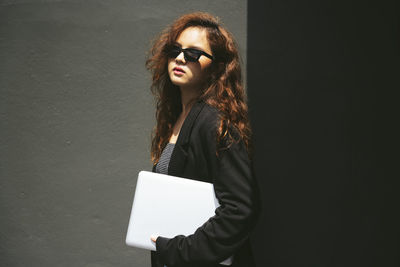 Portrait of woman standing against wall