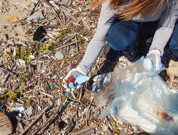 Low section of woman picking garbage outdoors