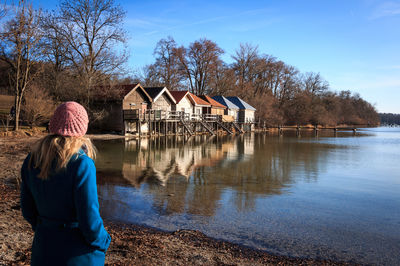 Rear view of man looking at lake against sky