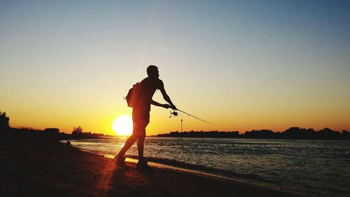 Silhouette of people on beach at sunset