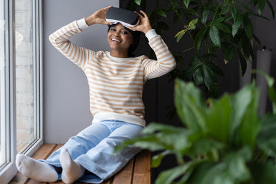 Happy woman wearing virtual reality glasses at home enjoy experience from new wearable technology vr