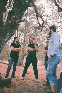 Full length of friends standing by tree against plants