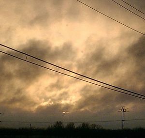 Low angle view of electricity pylon against cloudy sky