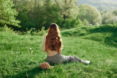 Rear view of woman sitting on grassy field