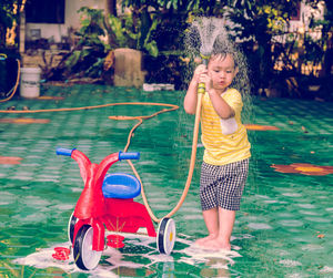 High angle view of boy washing tricycle outdoors