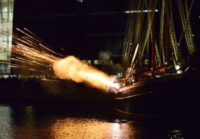 Firework display over river against sky in city at night