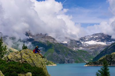 Man sitting by lake on mountain