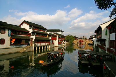 Boats in canal amidst buildings in city against sky