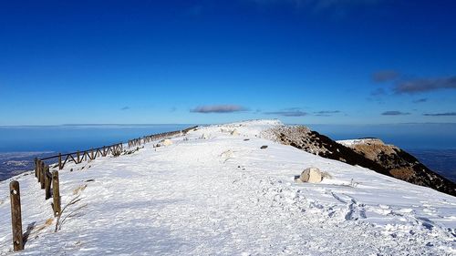 Scenic view of snow covered mountain against blue sky