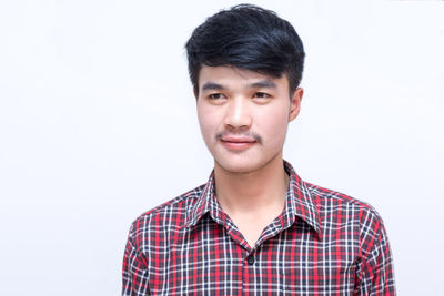 Portrait of young man standing against white background