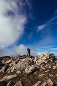 Low angle view of men on rock against sky