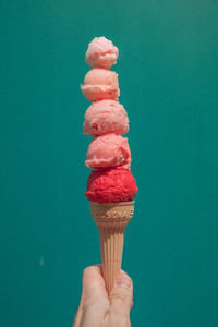 Hand holding ice cream cone against blue background