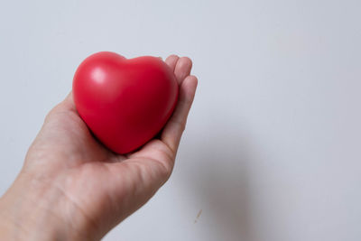 Close-up of hand holding heart shape against white background