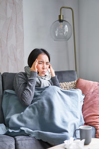 Young woman sitting on bed at home