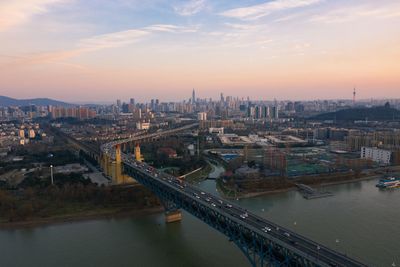 Aerial view of bridge over river by buildings against sky