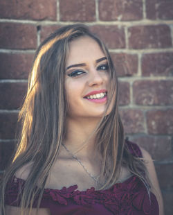 Portrait of beautiful young woman against brick wall