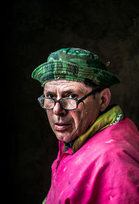 Close-up portrait of man wearing hat against black background