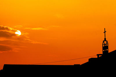 Low angle view of silhouette building against orange sky