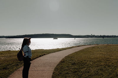 Full length of woman standing by lake against sky