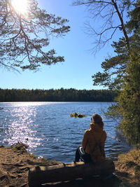 Man sitting by lake against trees