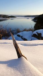 Snow covered land on field against sky during winter