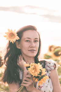 Portrait of beautiful young woman holding flower bouquet