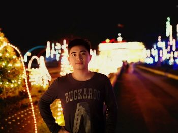 Portrait of young man standing in city at night
