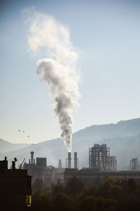 Smoke emitting from chimney against sky