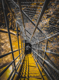 High angle view of yellow chainlink fence and graffiti artist