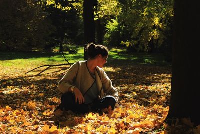 Woman sitting on field during autumn