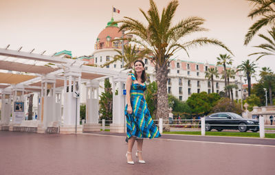 Portrait of young woman standing by palm trees