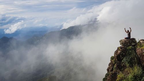 Man standing on rock against sky