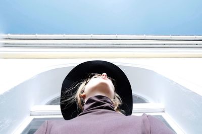 Low angle view of woman standing by building against sky