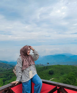 Side view of woman looking at park against sky