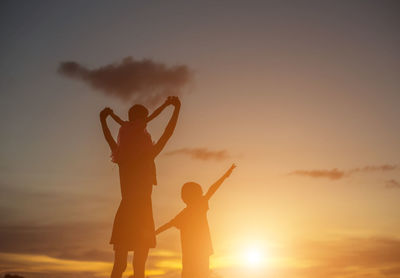 Silhouette people standing against sky during sunset