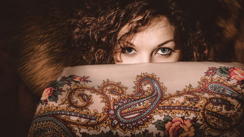 Portrait of beautiful woman hiding behind floral patterned fabric