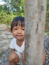 Portrait of smiling boy against tree trunk