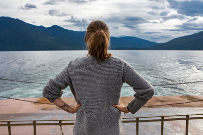 Rear view of woman looking at sea against mountains