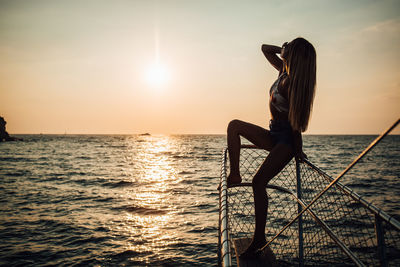 Woman standing on beach against sky during sunset