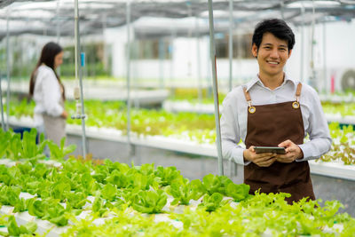 Portrait of smiling young woman standing in greenhouse