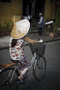 Rear view of woman riding bicycle on street