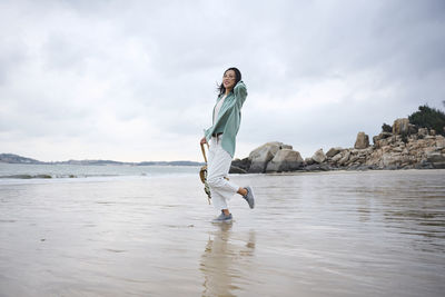Happy asian girl walking on the beach in autumn during her trip
