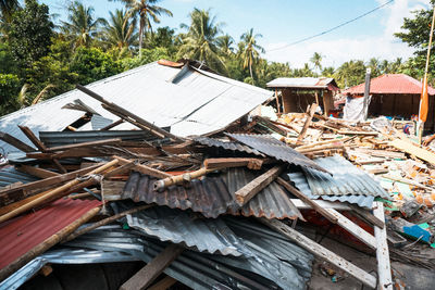 Stack of firewood by house roof against sky