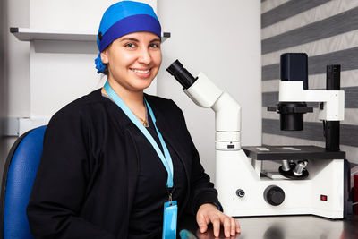 Beautiful young female scientist in the laboratory next to an inverted microscope