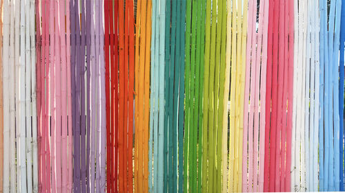 Rainbow bamboo wall in the bright concept of a long segmen painted in multicolored use background.